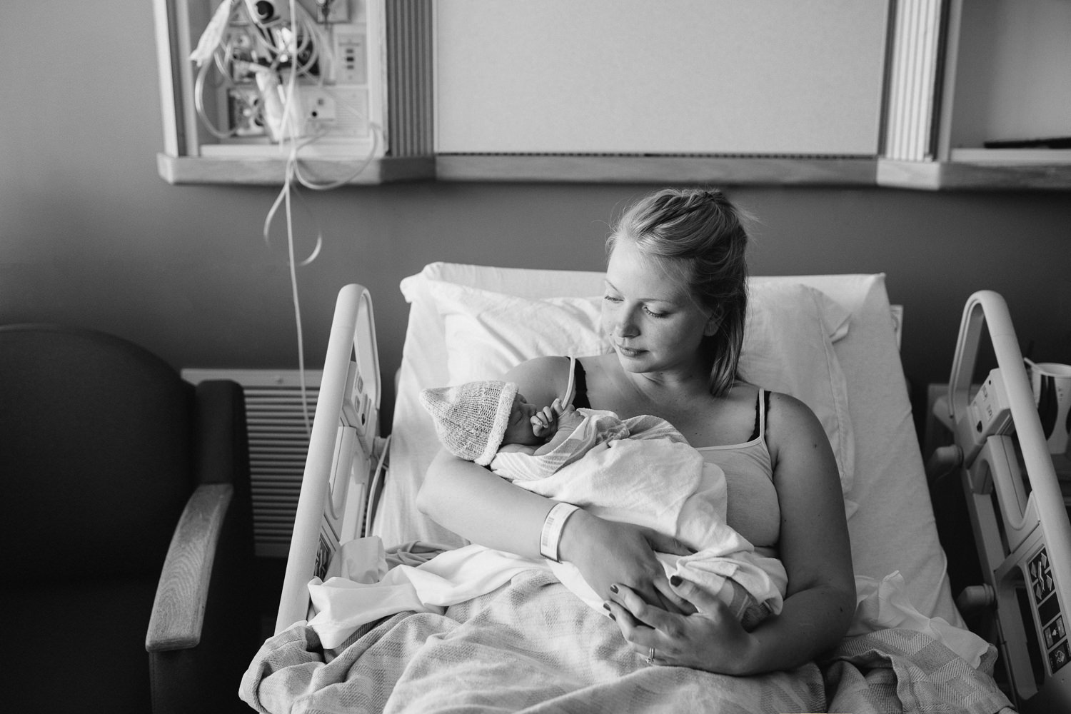 first time mom sitting in hospital bed holding 10 hour old baby boy - Markham Fresh 48 Photography