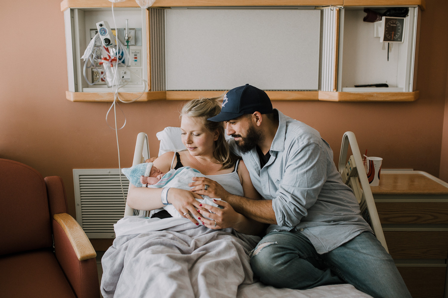 brand new parents sitting in hospital bed holding and looking at 10 hour old baby boy - Stouffville Fresh 48 Photos