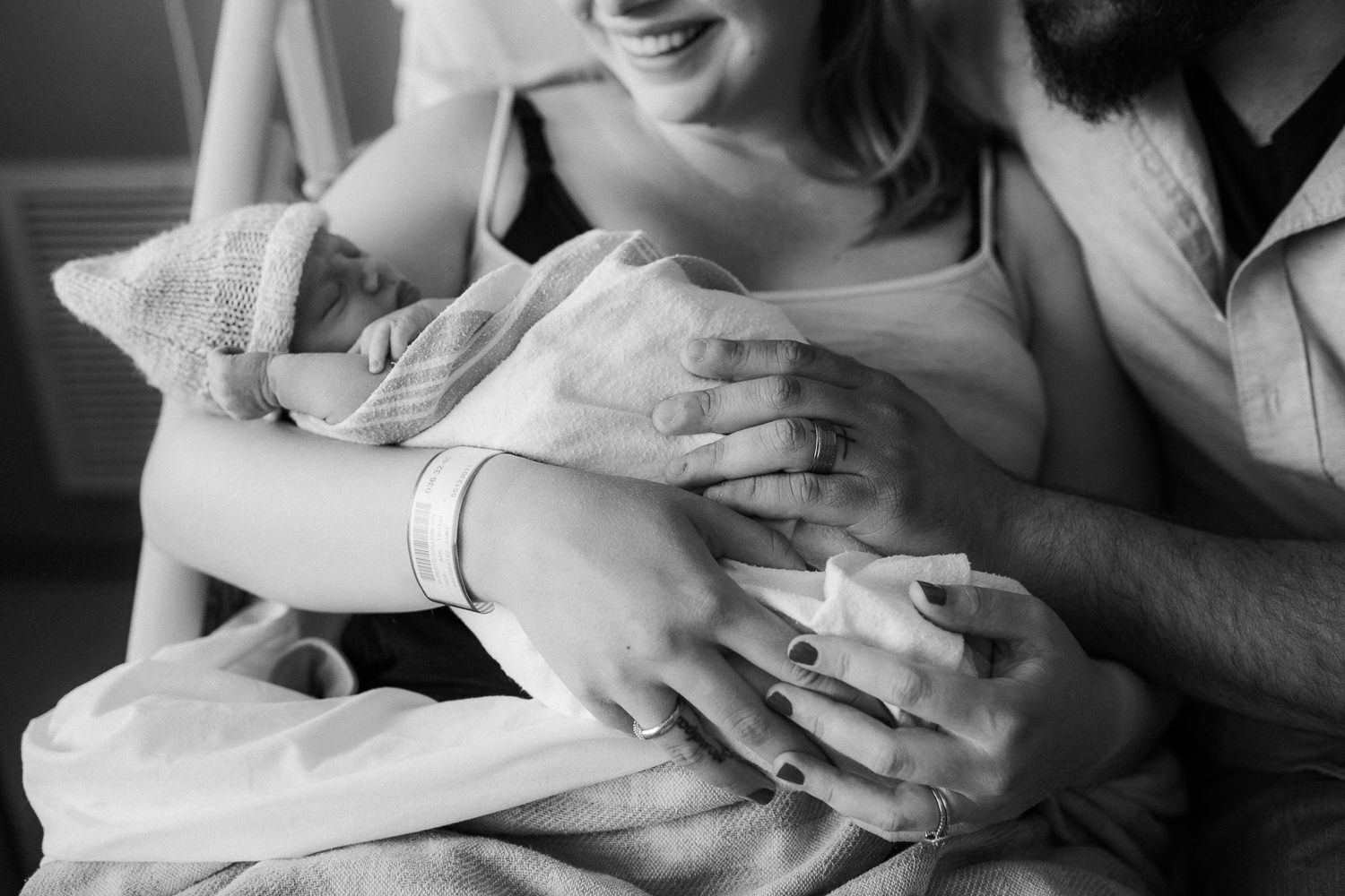 brand new parents sitting in hospital bed holding and looking at 10 hour old baby boy - Markham Fresh 48 Photos