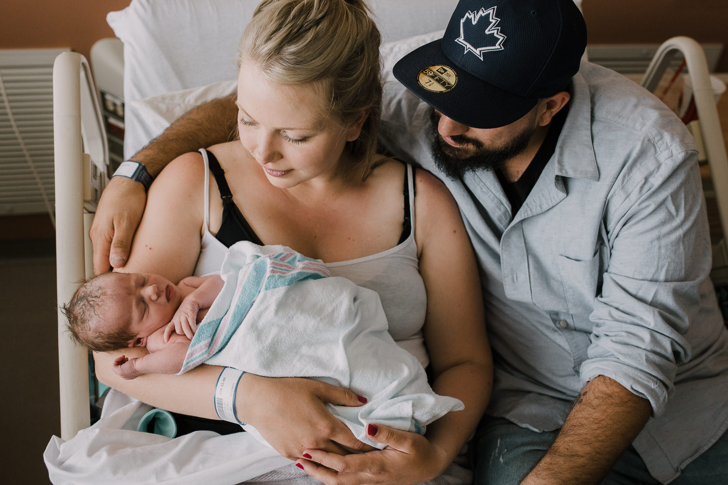 brand new parents sitting in hospital bed holding and looking at 10 hour old baby boy - Barrie Fresh 48 Photos