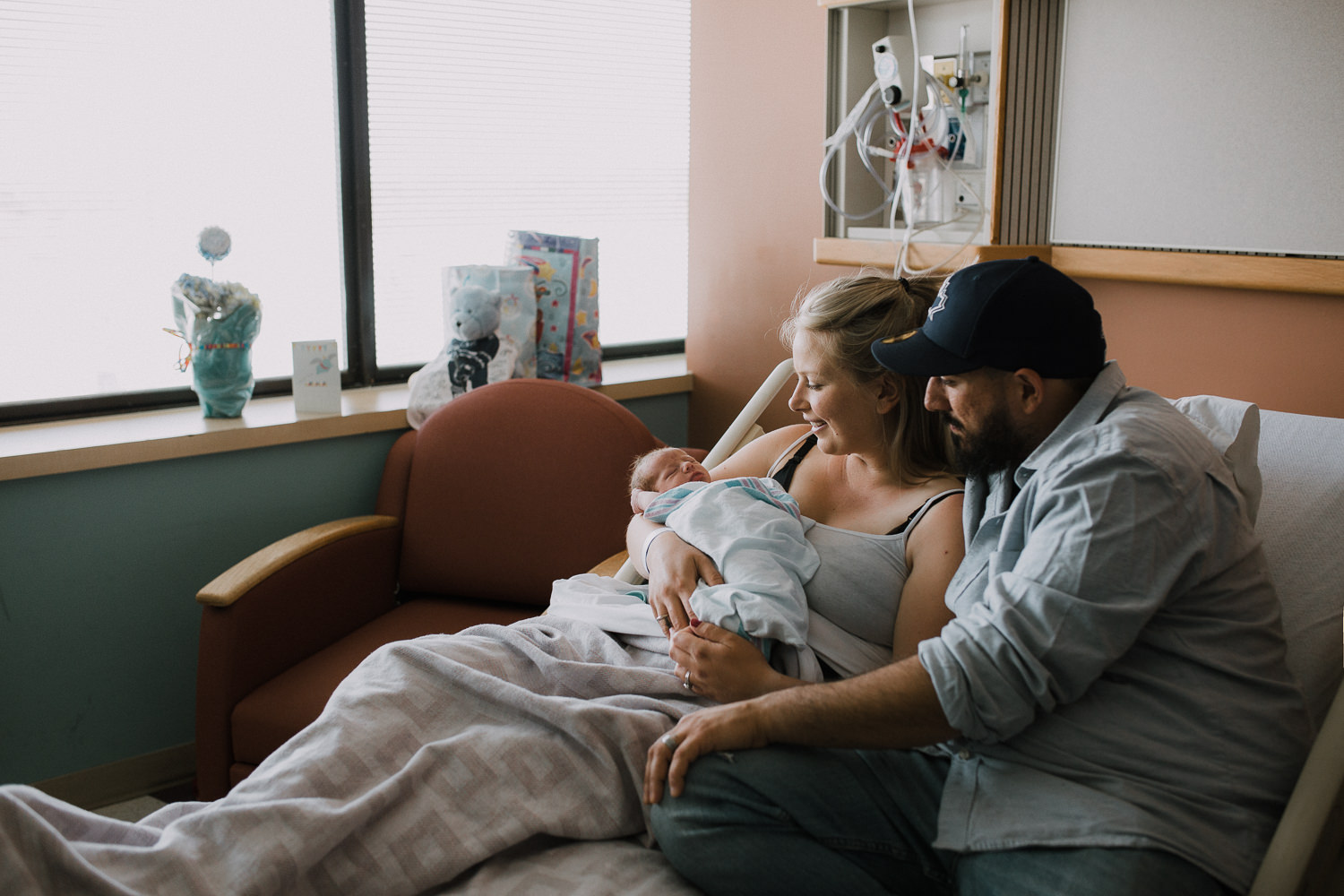 first time parents sitting in hospital bed holding and looking at 10 hour old baby boy - Barrie In-Hospital Photos