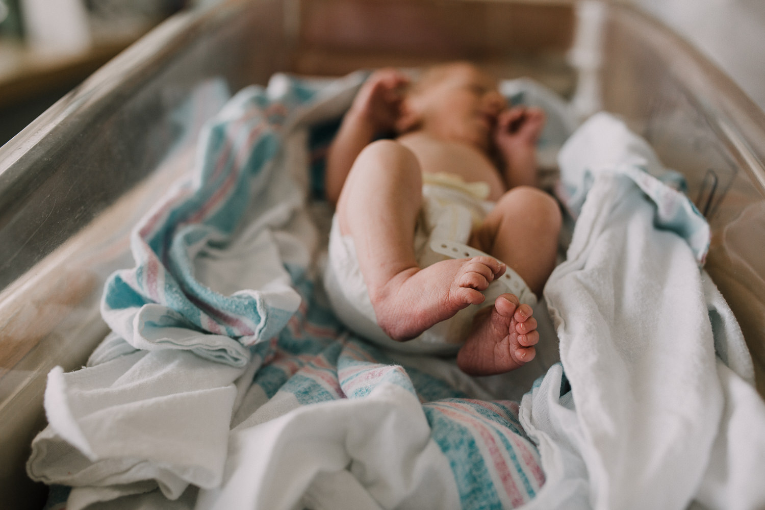 10 hour old baby boy in diaper sleeping in hospital bassinet, closeup of feet - Newmarket Fresh 48 Photography