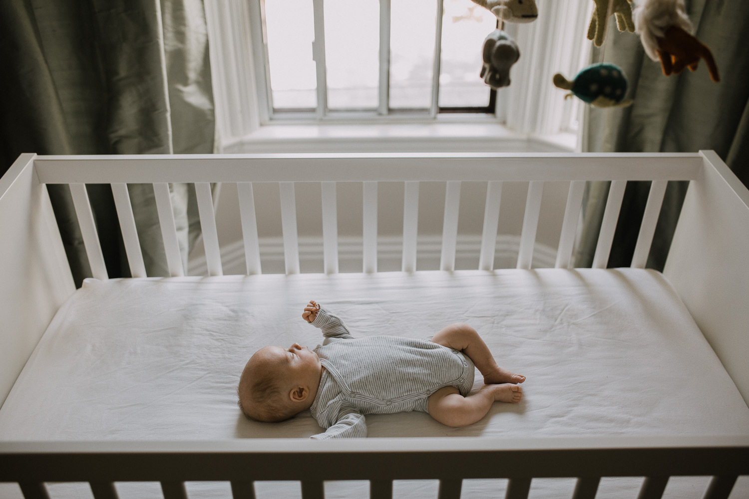 2 week old baby boy in grey onesie sleeping in nursery crib - Newmarket Lifestyle Photography