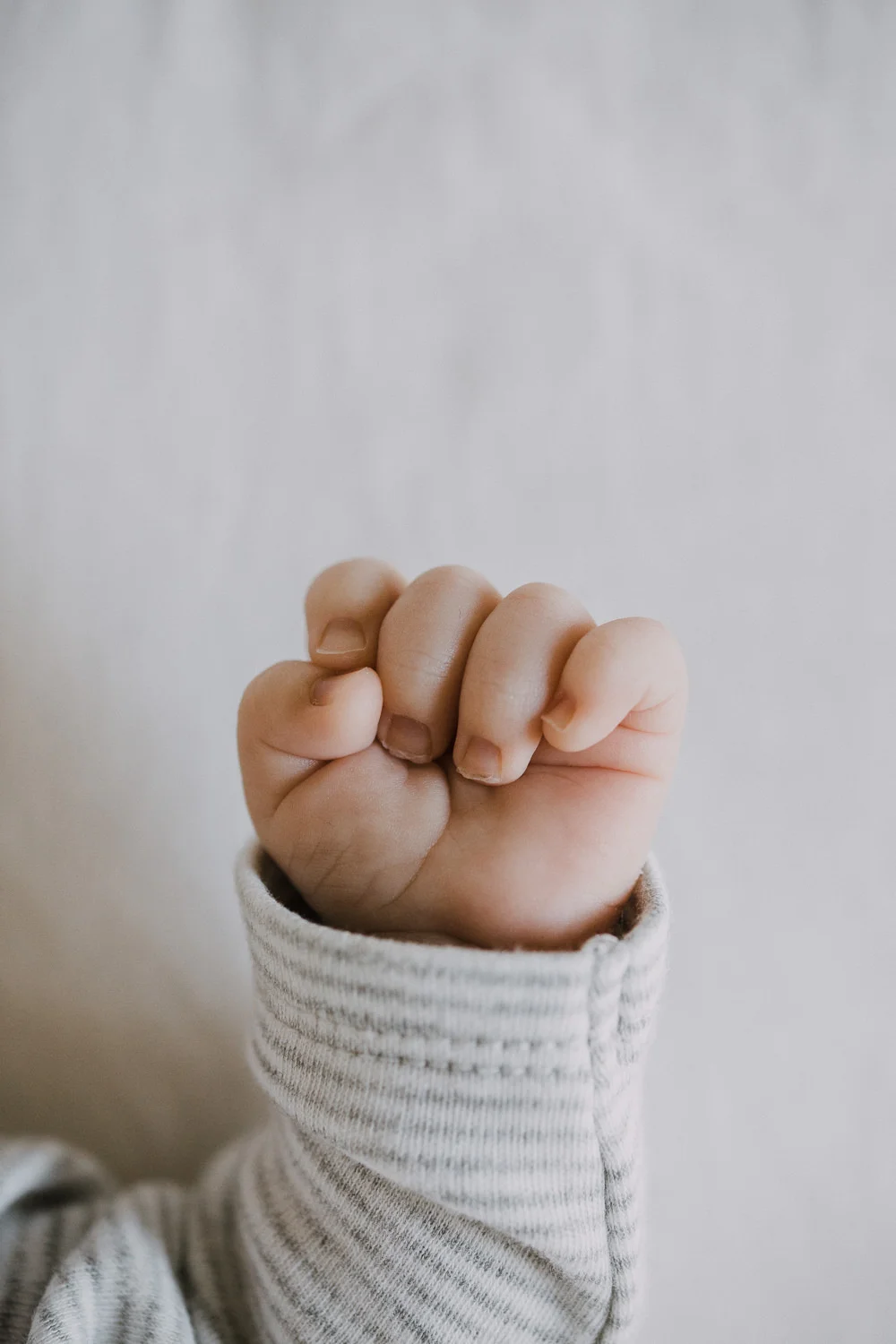 2 week old baby boy in grey striped onesie, close up of hand - Newmarket In-Home Photography