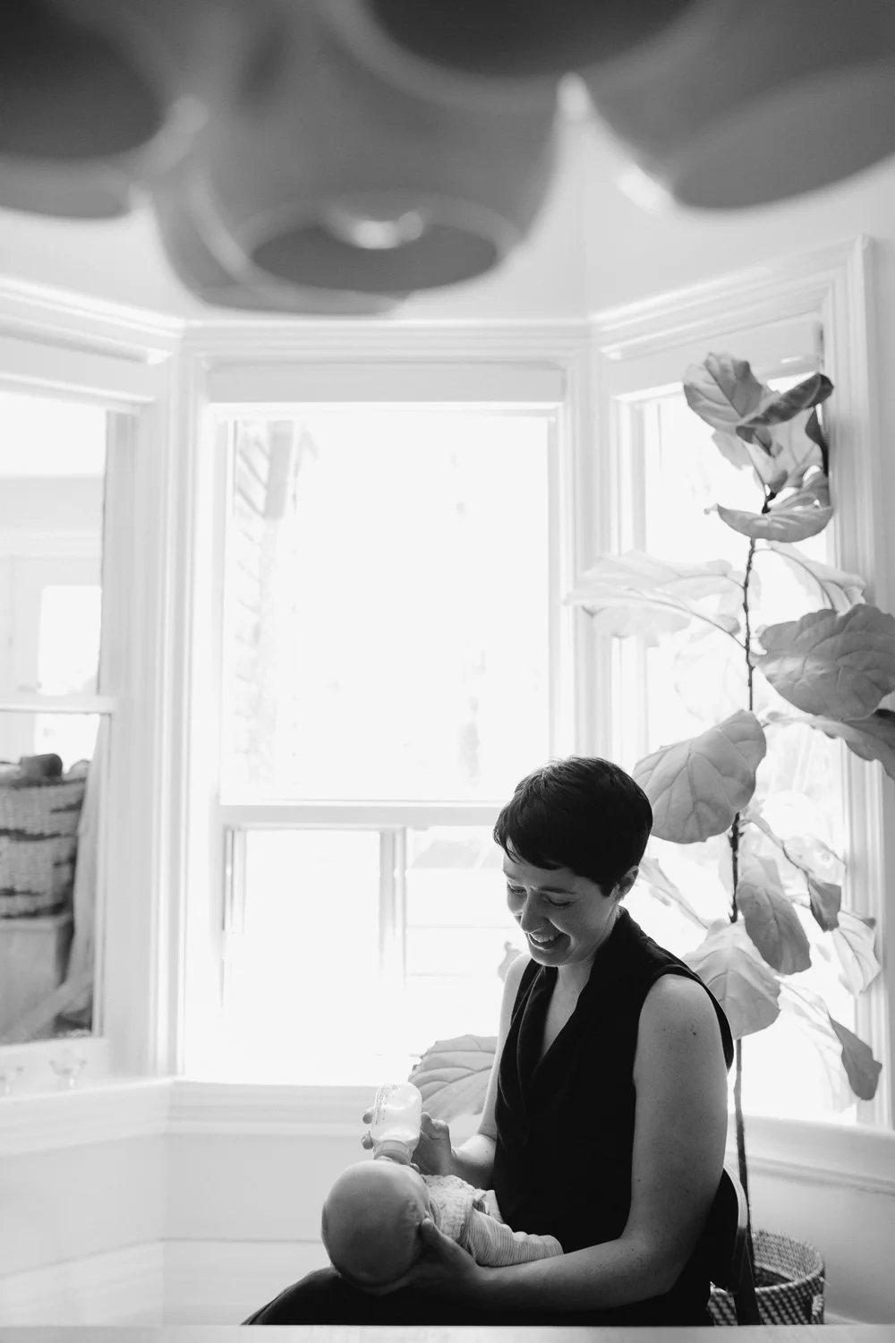 first time mom sitting in dining room chair bottle feeding 2 week old baby boy - Markham Lifestyle Photos