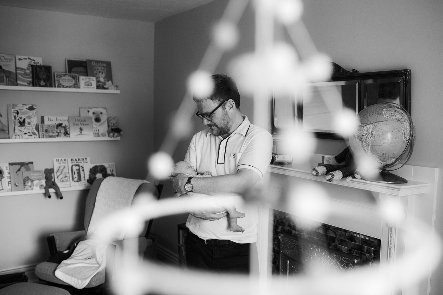 first time father standing in nursery holding and looking at 2 week old baby boy - Barrie In-Home Photography