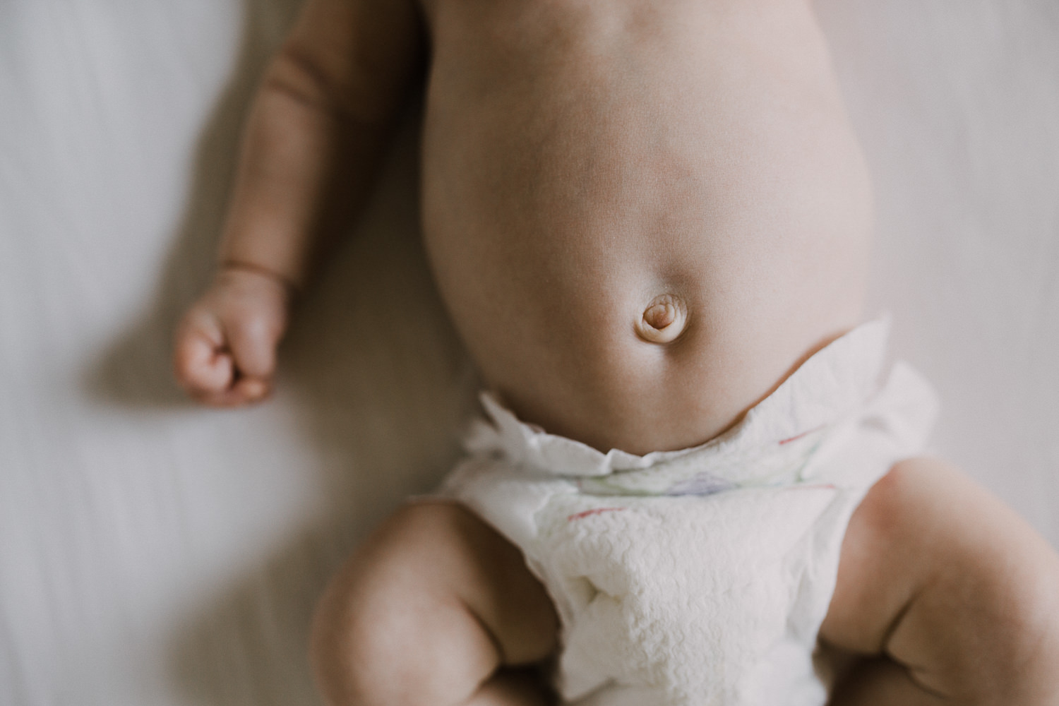 2 week old baby boy in diaper sleeping in nursery crib, close up of belly button - Barrie In-Home Photography