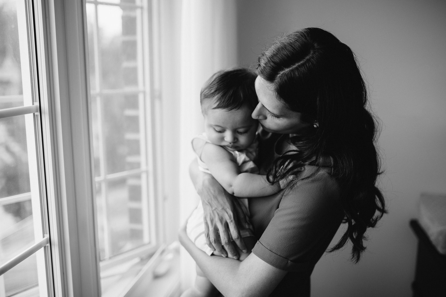 mom standing at window embracing 8 month old baby boy - Stouffville Lifestyle Photos