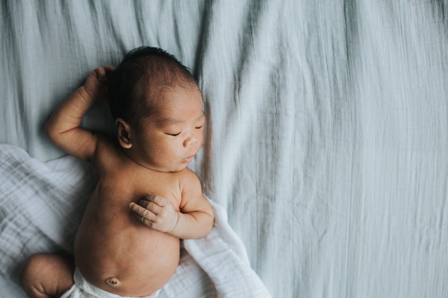 2 week old baby boy in diaper asleep with arm behind head - Barrie Lifestyle Photography