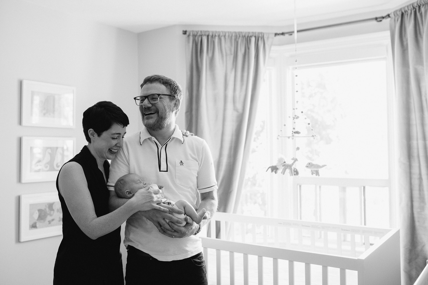 laughing parents standing in nursery holding sleeping baby boy - Barrie In-Home Photography