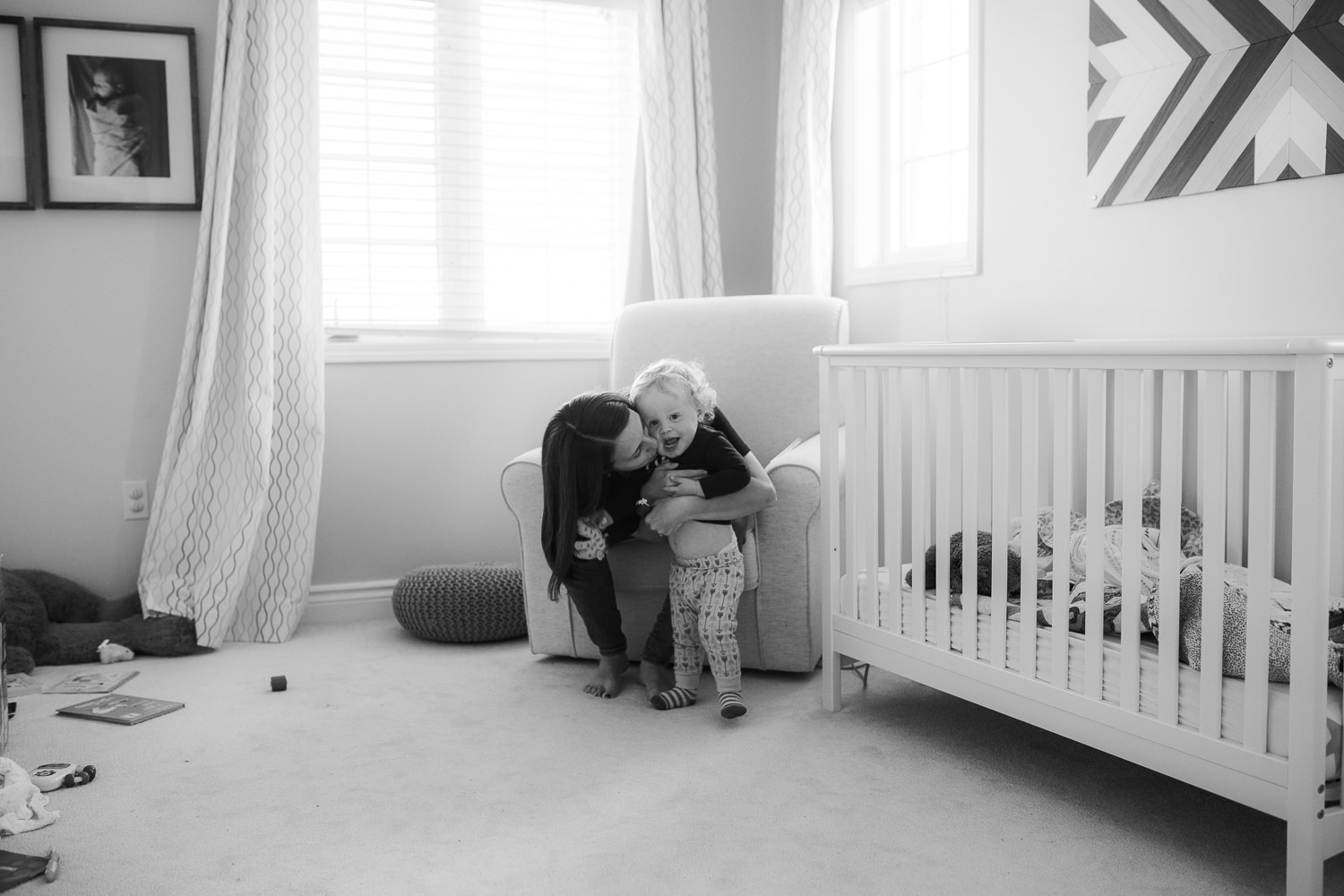 mom kissing and hugging 18 month old son in nursery - Newmarket Documentary Photographer