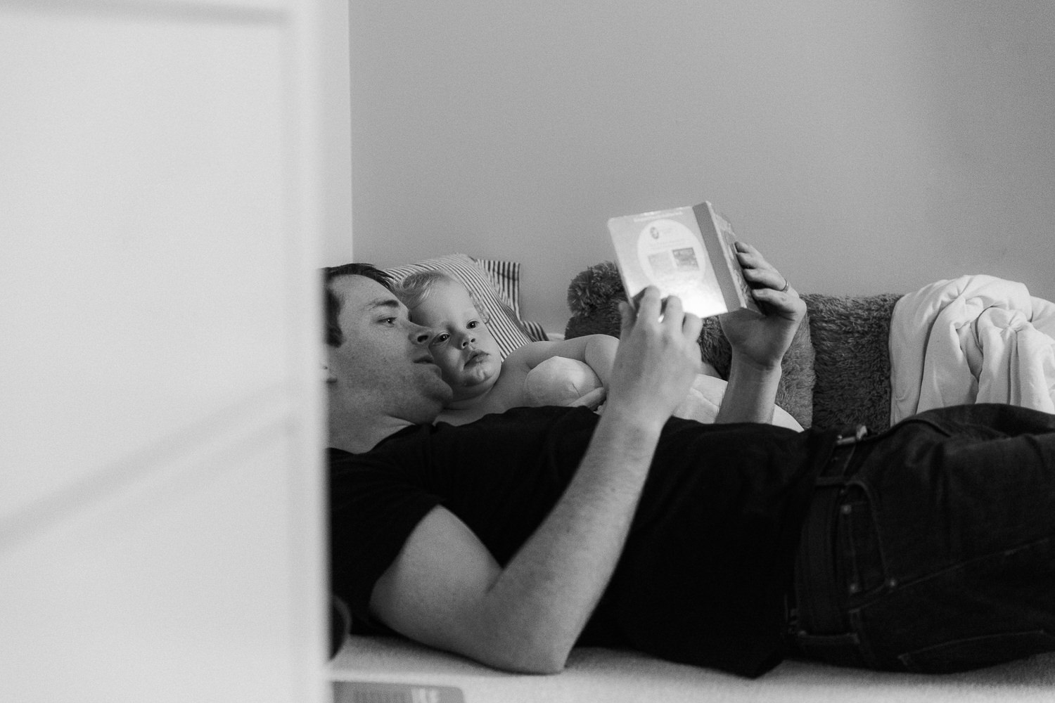 dad and toddler son lying on floor reading bedtime story - Newmarket Documentary Photography