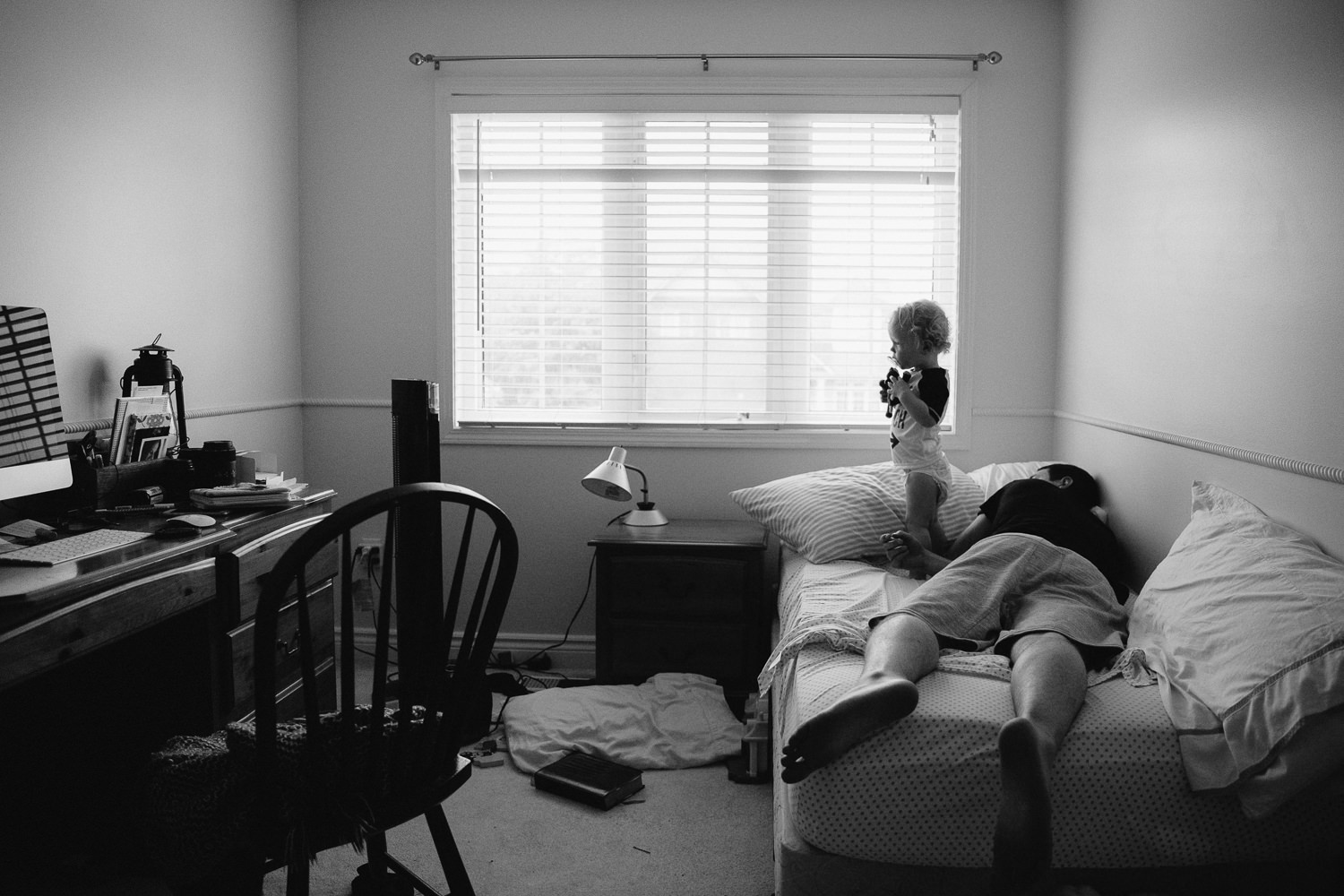 toddler boy standing on bed and dad sleep on bed - Barrie Family Photography