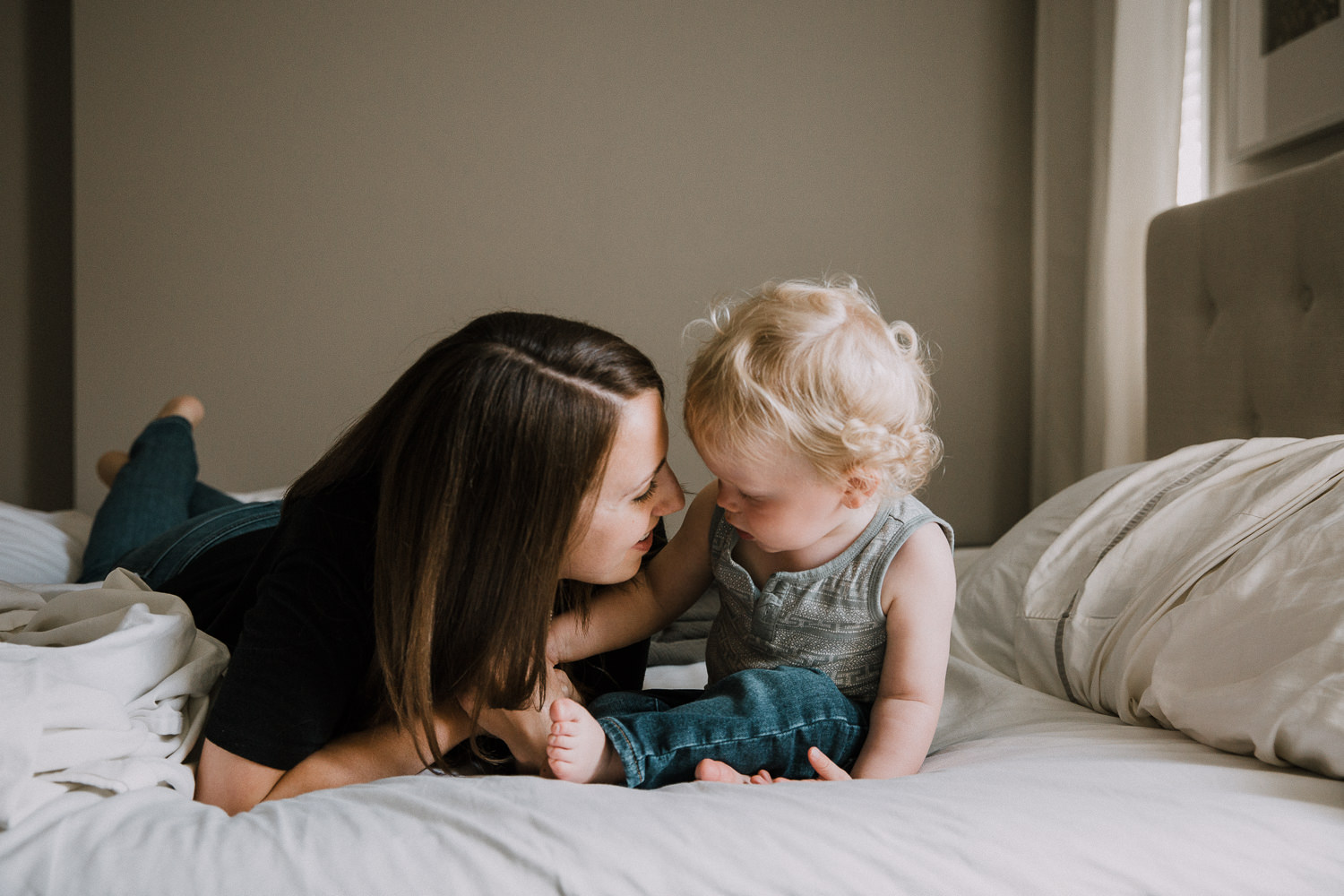 mom and blonde toddler son lying on bed, heads together - Markham Family Photographer