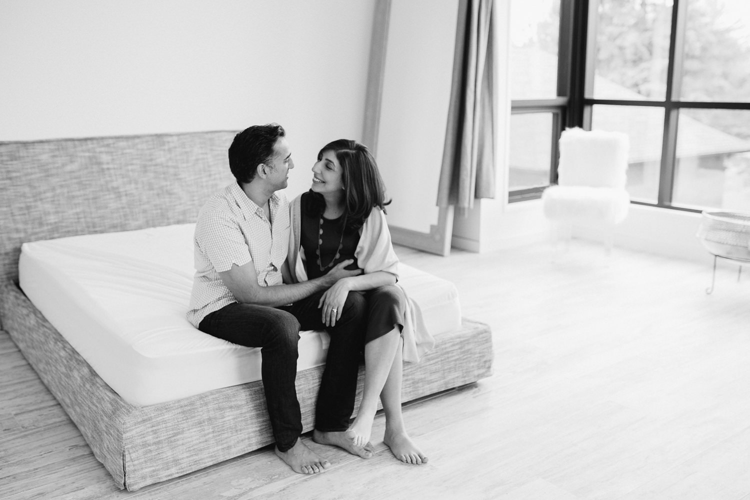 expectant parents sitting at end of bed, pregnant wife smiling at husband - Newmarket In-Home Photos