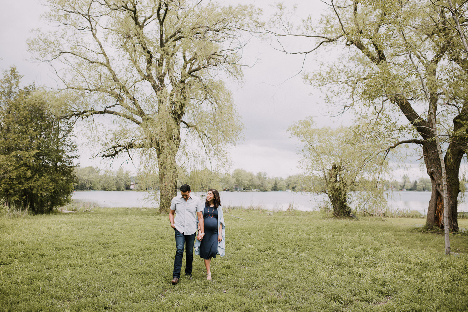 parents-to-be holding hands and walking away from the lake - Stouffville In-Home Photos