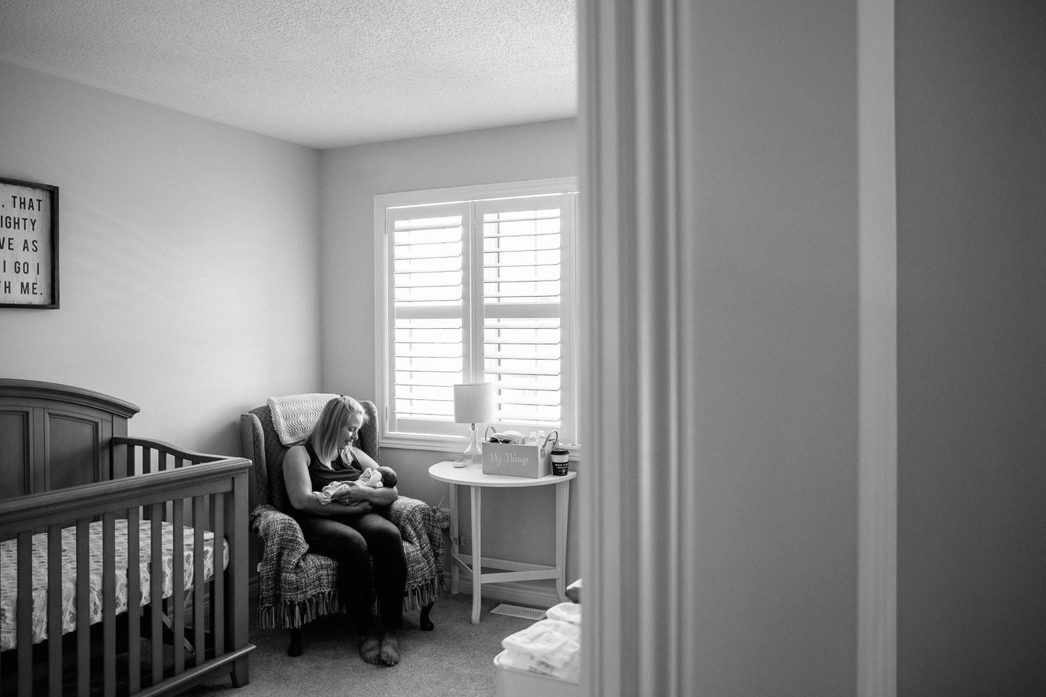 new mom sitting in nursery chair holding 2 week old baby boy - Newmarket Lifestyle Photography