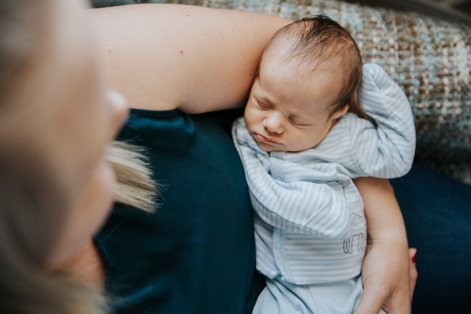 2 week old baby boy in blue sleeper lying asleep in mom's arms - Markham Lifestyle Photography