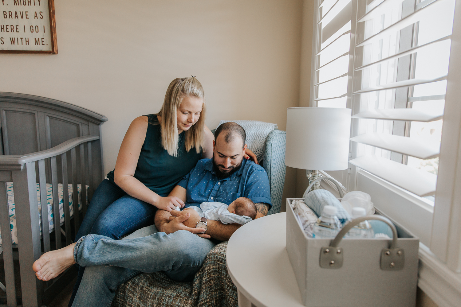 new parents sitting in nursery chair holding sleeping 2 week old baby boy - Markham In-Home Photography