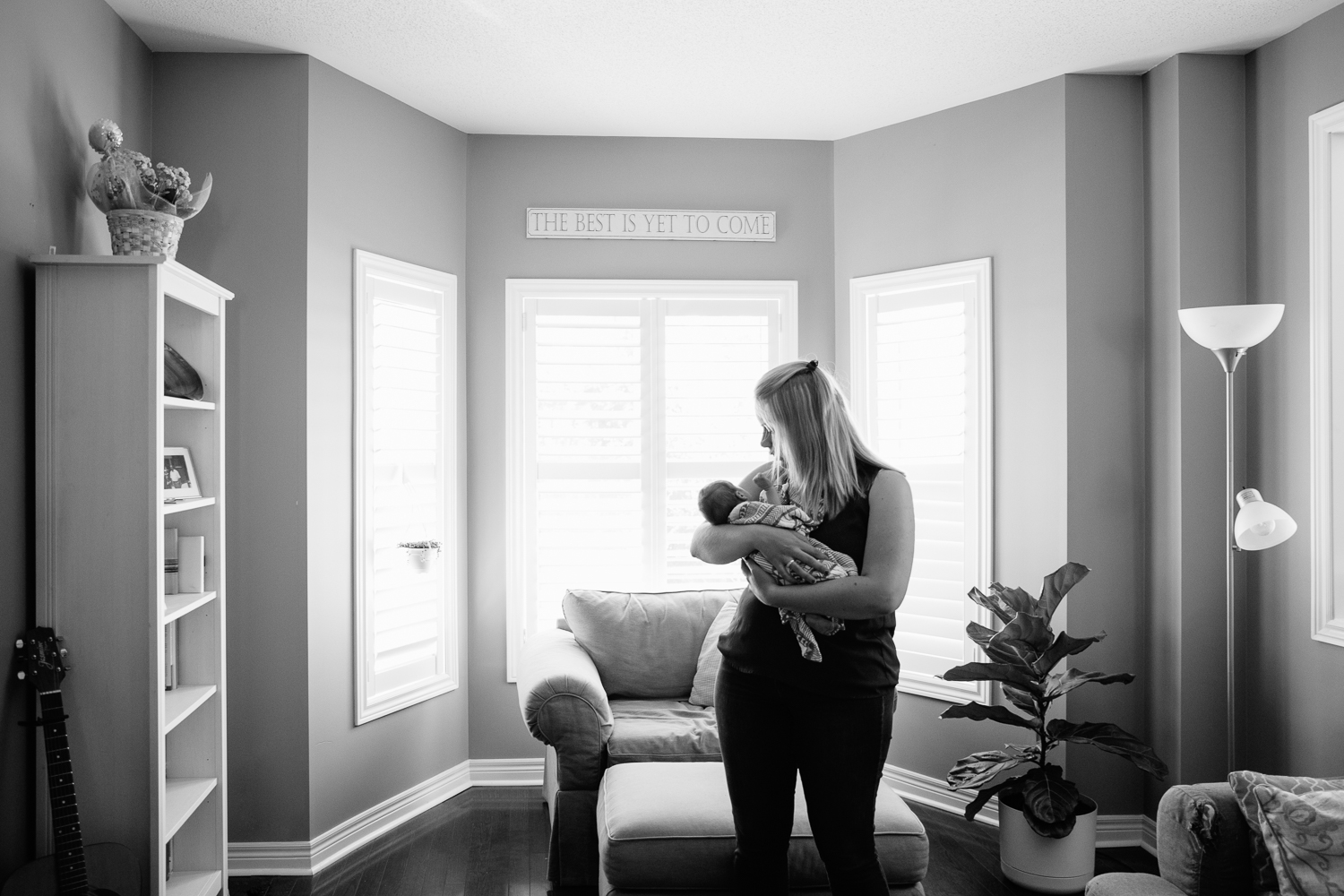 new mom standing in front of window rocking 2 week old baby boy to sleep - Newmarket Lifestyle Photography