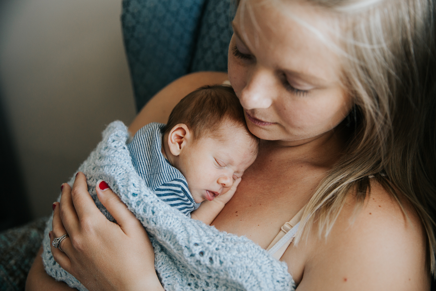 new mom sitting in rocking chair with 2 week old baby boy sleeping snuggled to her chest - Barrie Lifestyle Photography