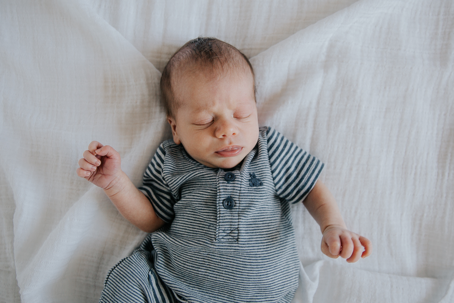 2 week old baby boy in blue outfit sleeping on bed - Barrie In-Home Photography