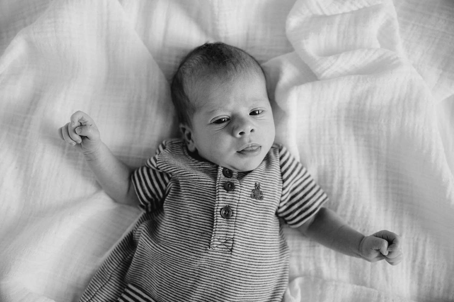 2 week old baby boy lying on bed, looking at camera - Stouffville In-Home Photos