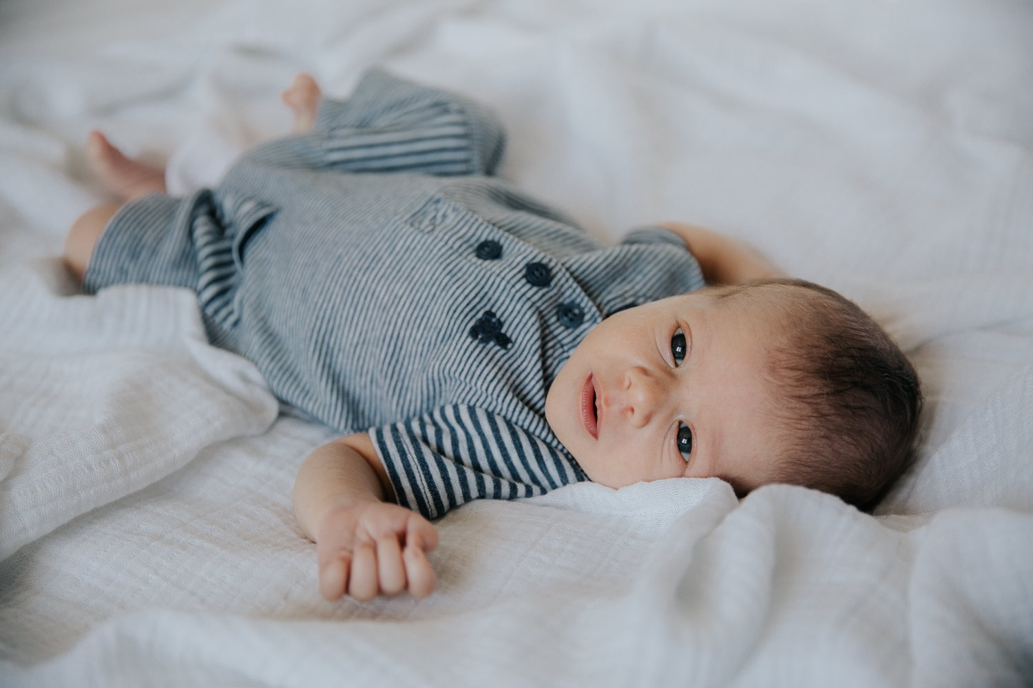 2 week old baby boy lying on bed, looking at camera - Markham In-Home Photos