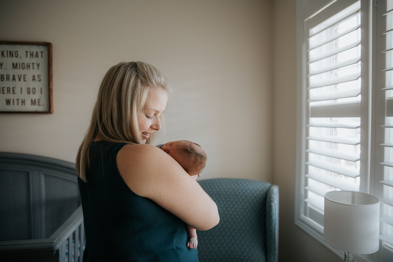 first time mom standing in nursery holding sleeping 2 week old baby son - Stouffville Lifestyle Photography