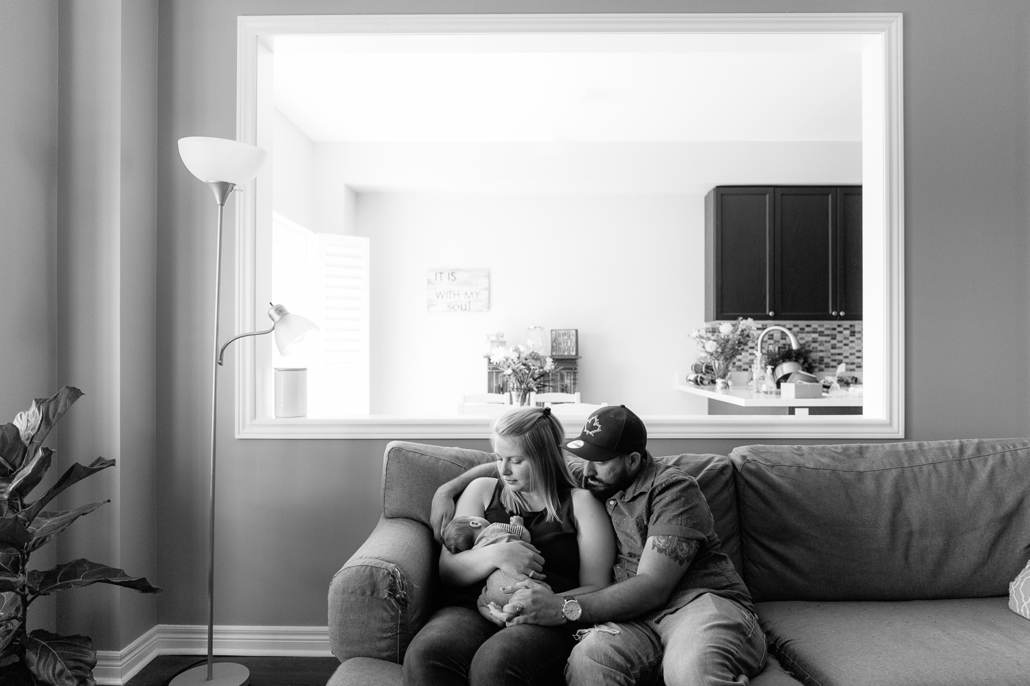 new parents sitting on couch holding and looking at 2 week old baby son - Barrie Lifestyle Photography