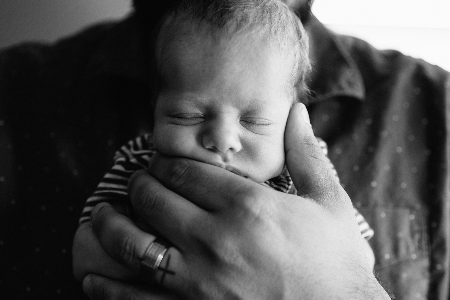2 week old baby boy sleeping with chin resting in father's hand - Newmarket Lifestyle Photos