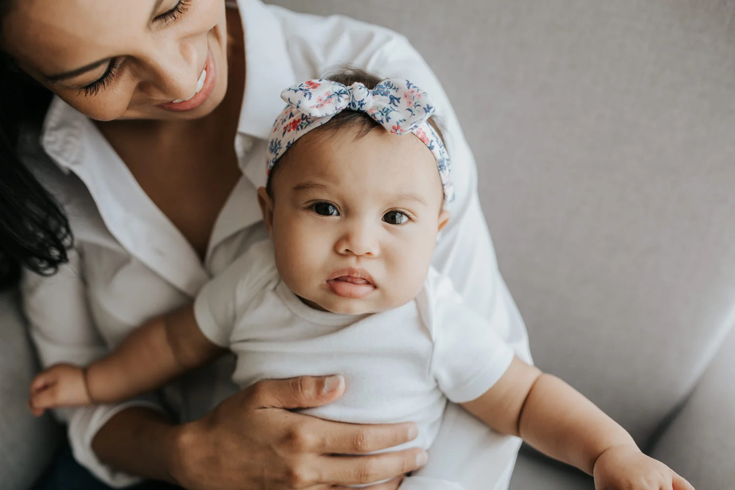 mom sitting in glider holding 6 month old daughter in her lap, baby girl looking at camera - Barrie Lifestyle Photography