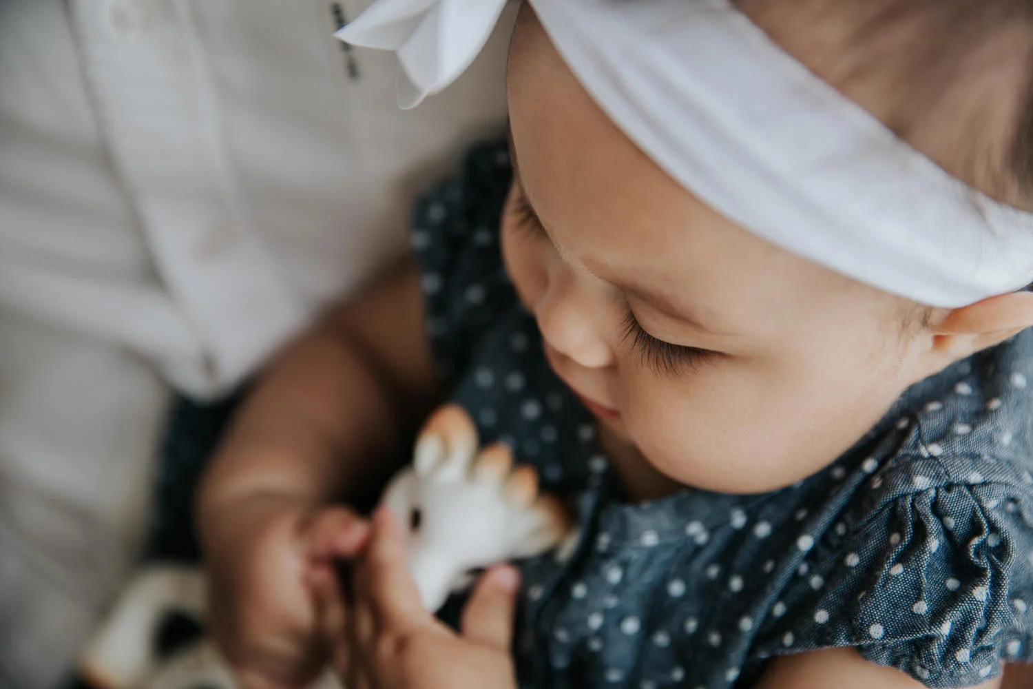 close up of 6 month old baby girls dark eyelashes as she play with Sophie the Giraffe - Barrie In-Home Photography