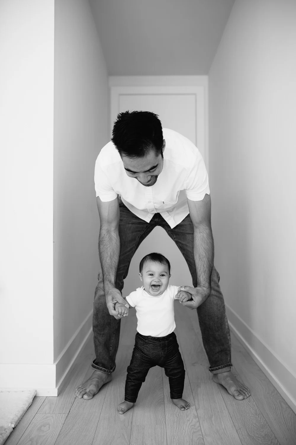 6 month old baby girl walking and laughing, holding onto dad's hands - Barrie Lifestyle Photos