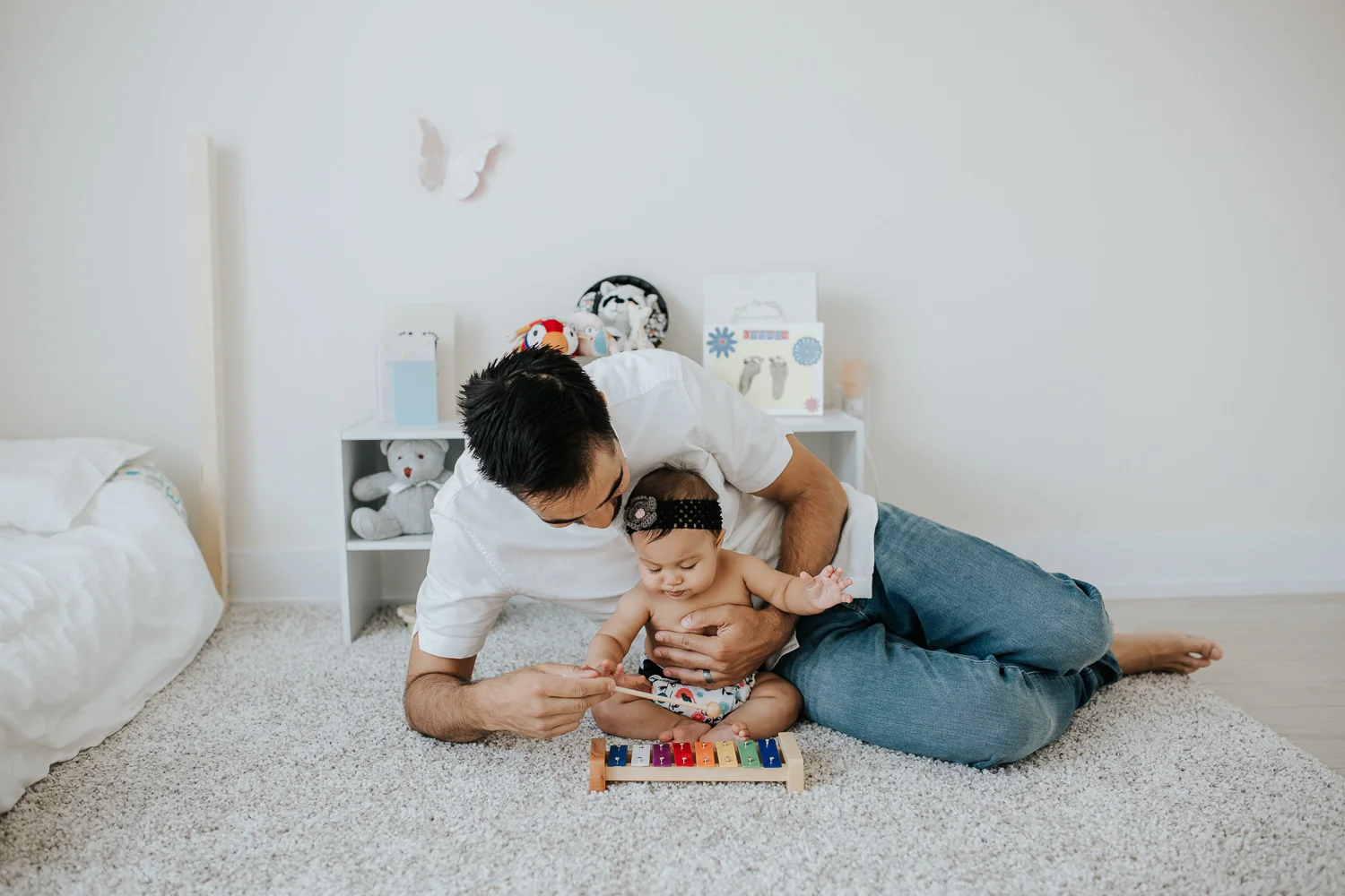 father and 6 month old baby daughter on nursery floor playing with xylophone - Markham In-Home Photography