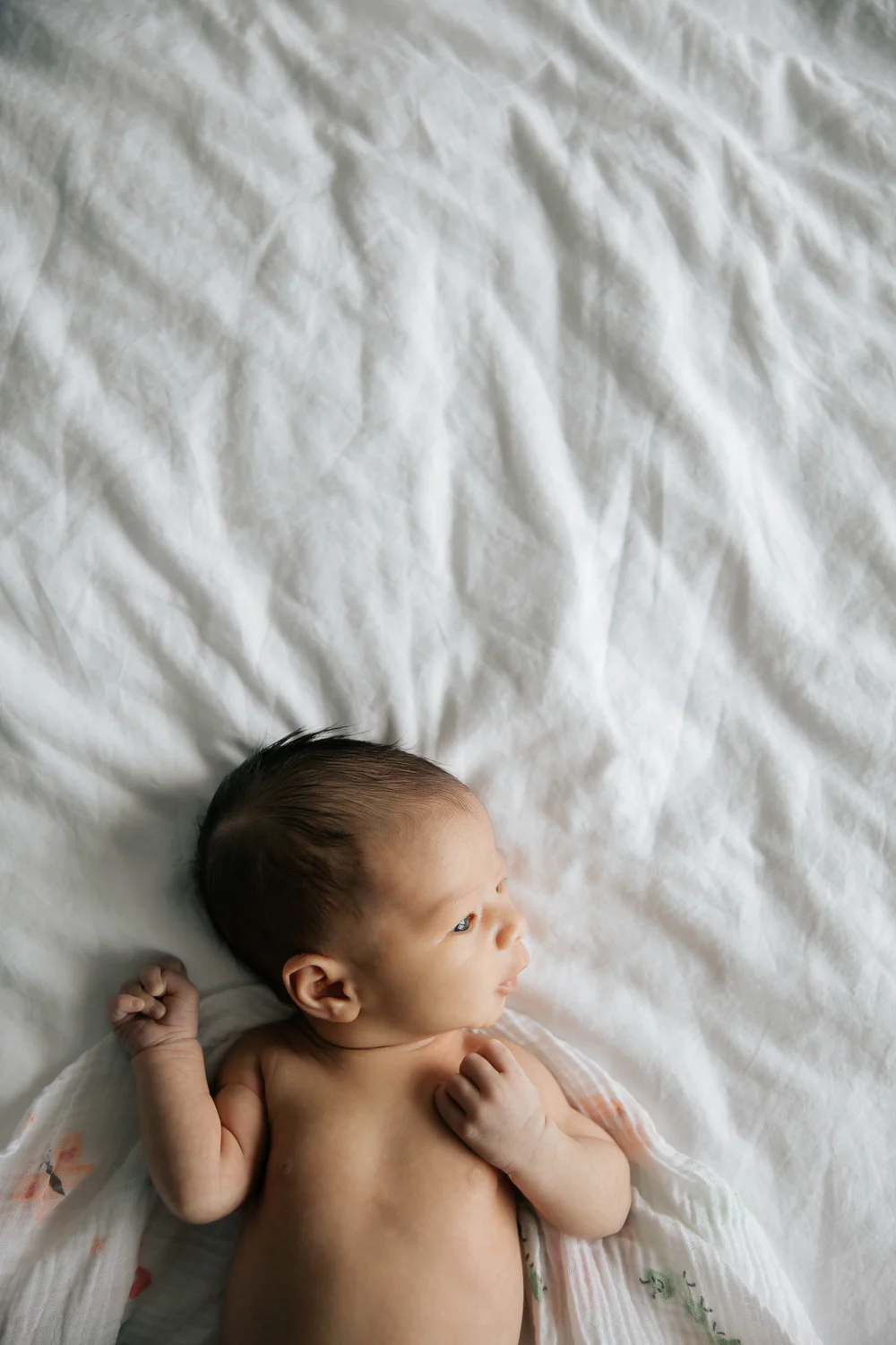 2 week old baby girl in diaper lying on bed awake - Newmarket Lifestyle Photos