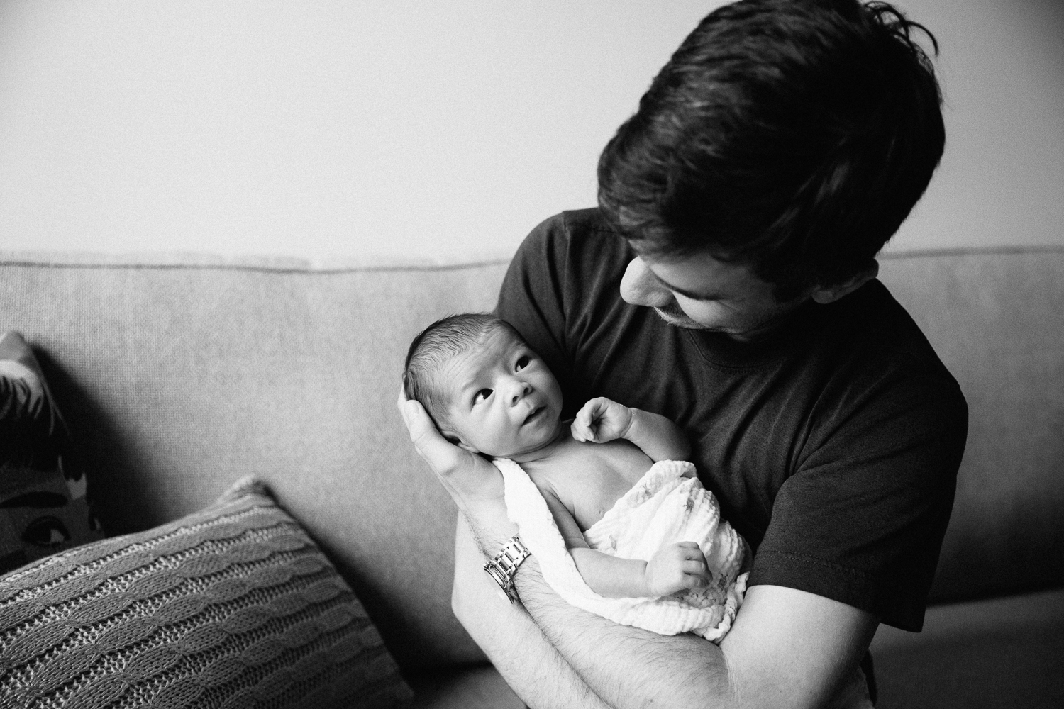 new dad holding 2 week old swaddled baby girl who is giving dad a funny look - Stouffville In-Home Photography