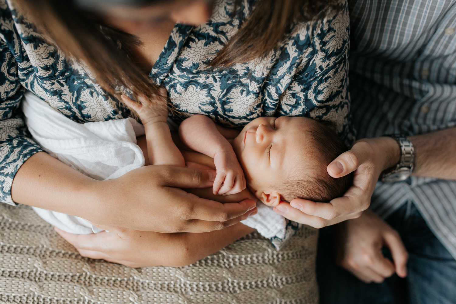 first time parents sitting on couch holding sleeping 2 week old baby girl - Barrie Lifestyle Photos