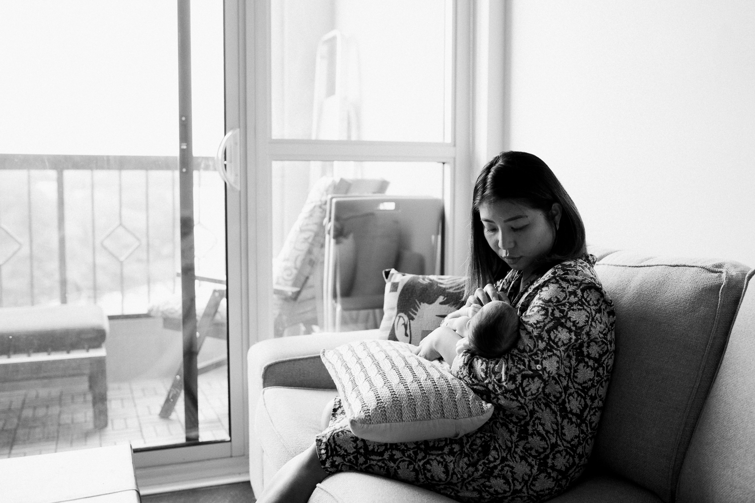 new mother sitting on couch holding sleeping 2 week old baby girl - Newmarket Lifestyle Photography