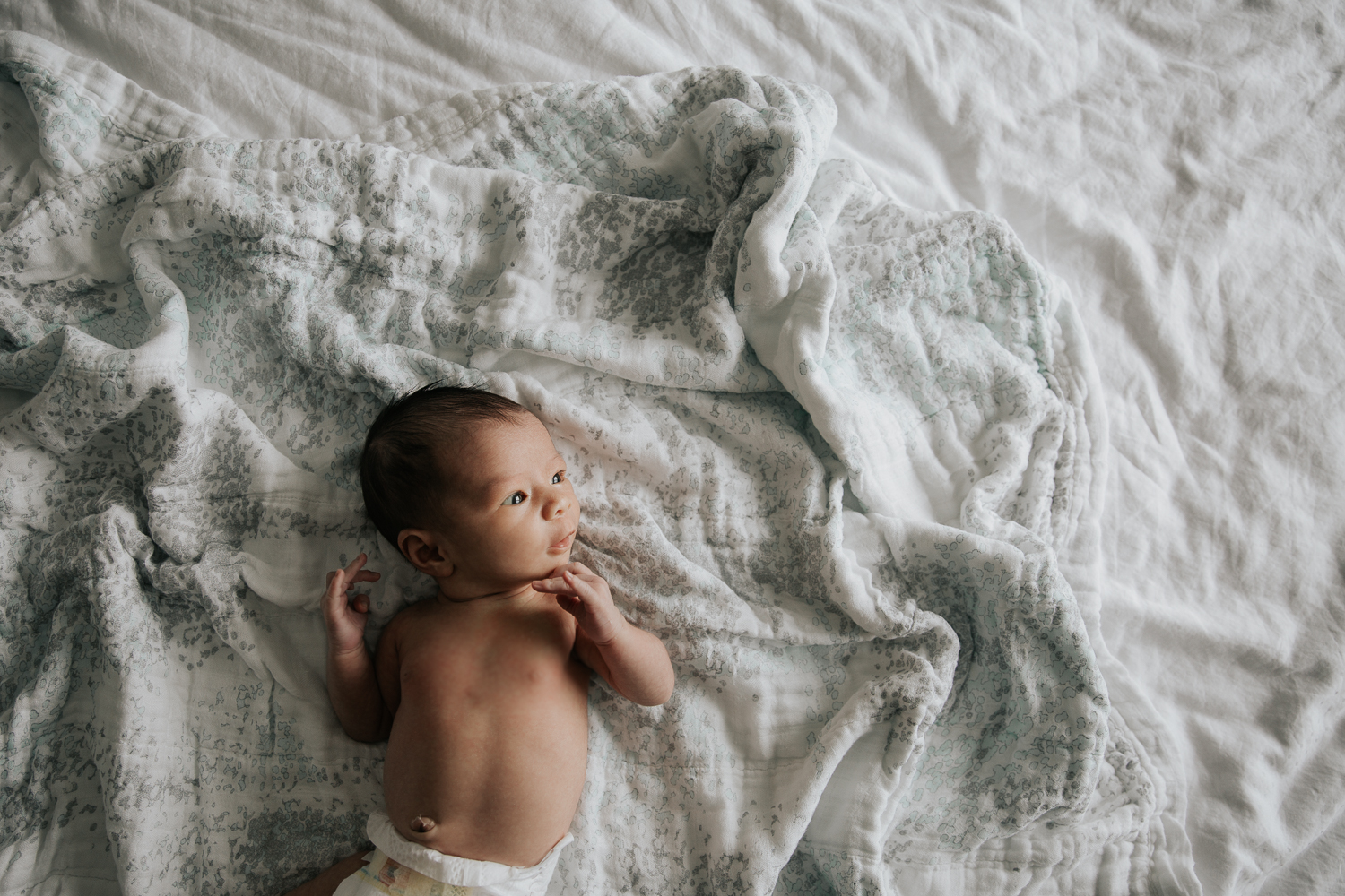 2 week old baby girl in diaper lying on bed awake - Markham In-Home Photography