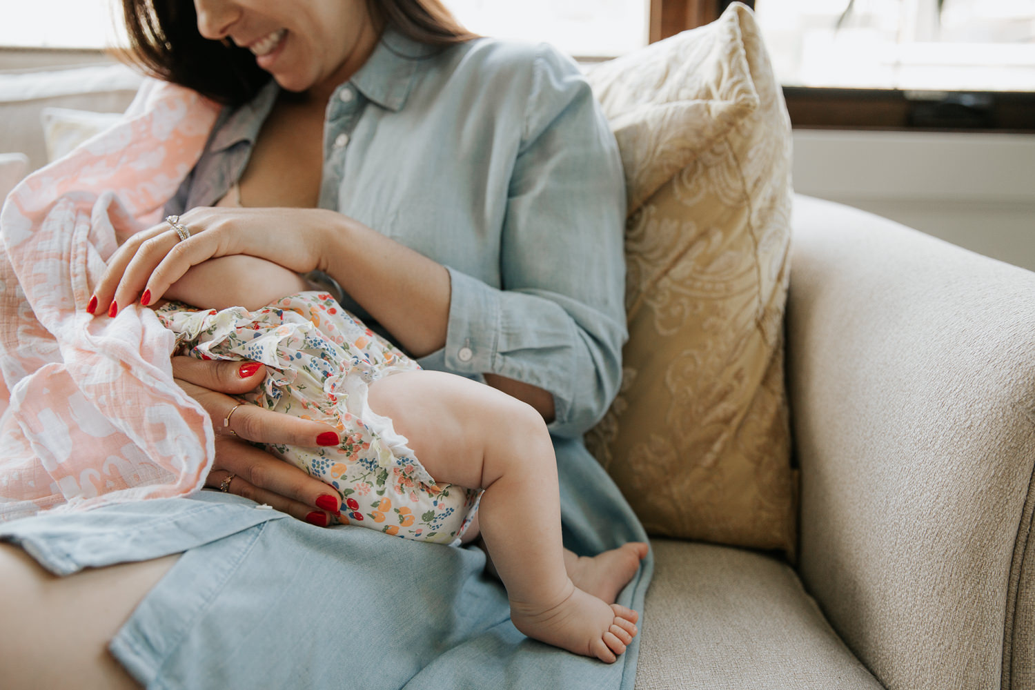 new mother sitting on couch nursing 2 month old baby girl in floral jumper, close up of baby's feet - Newmarket Lifestyle Photography