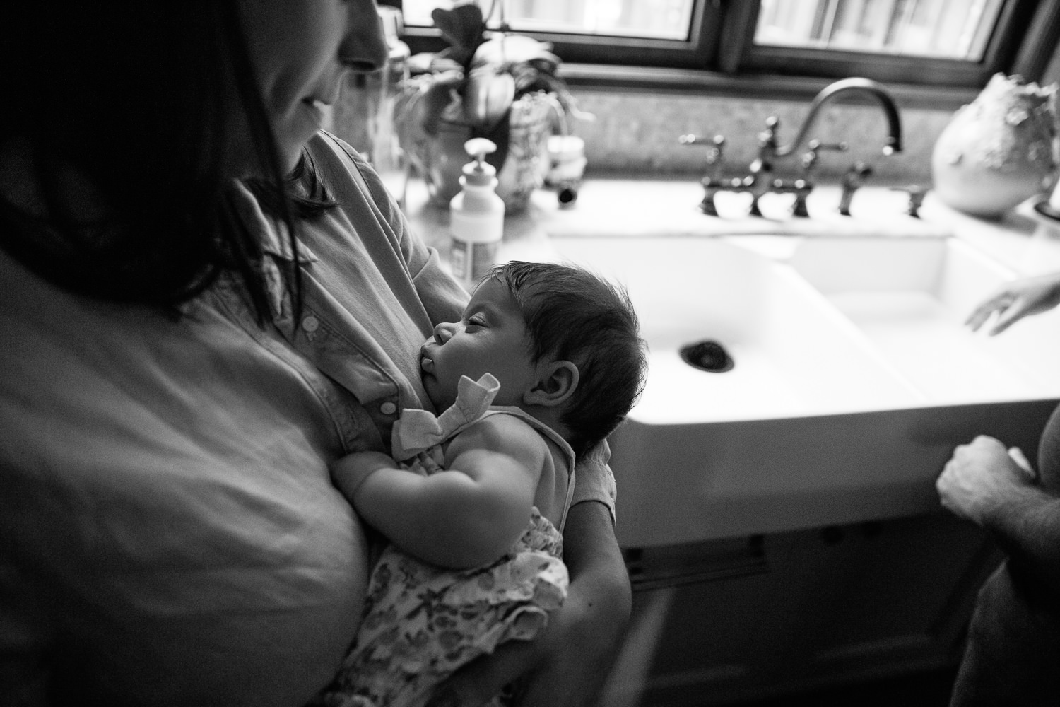 new mother standing in kitchen with 2 month old baby girl snuggled asleep on her chest - Barrie Lifestyle Photography