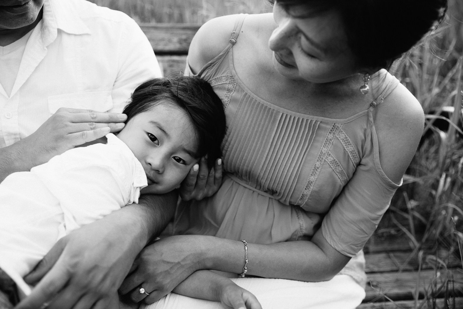 3 year old boy lying in dad's lap, mom sitting next to them, son looking at camera -  Newmarket In-Home Photography