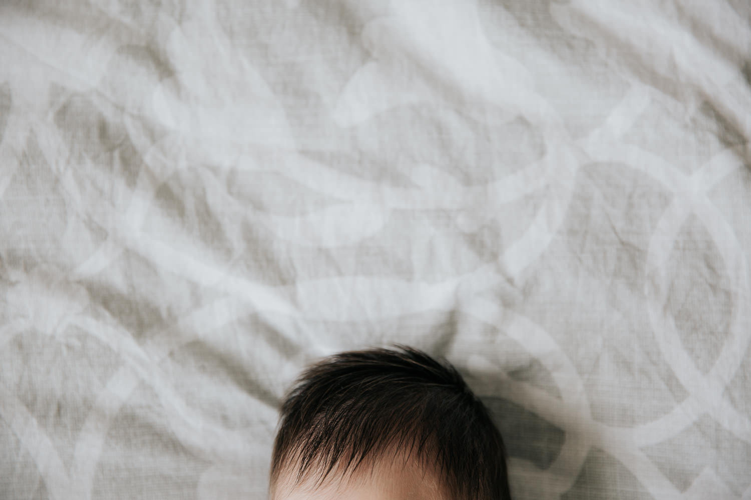 2 week old baby girl with lots of dark hair lying on bed, close up of hair - Newmarket In-Home Photography