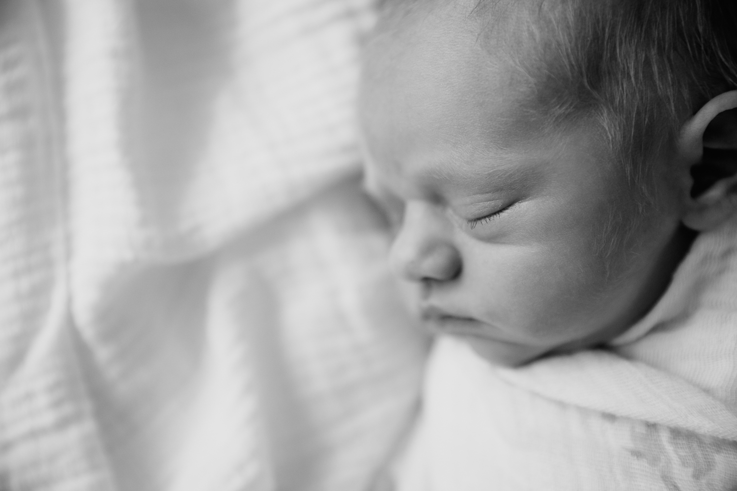 3 week old swaddled baby boy with red hair sleeping on bed, side profile of face - Barrie In-Home Photos