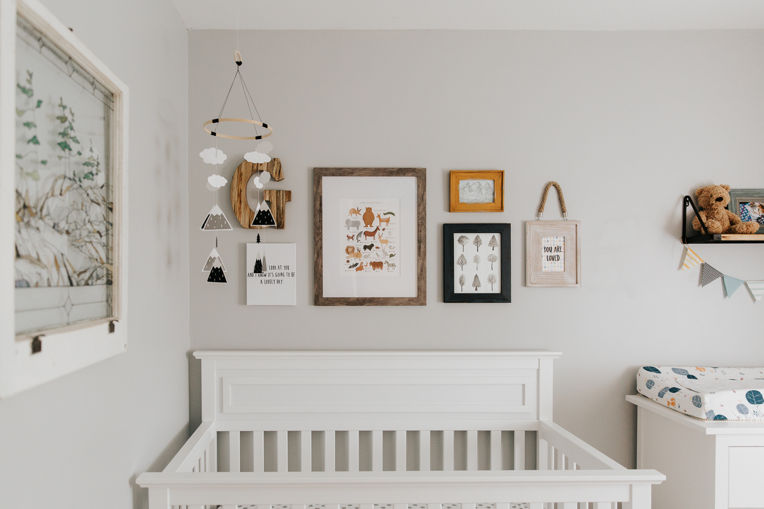 nursery details, grey walls, white crib with a gallery wall containing woodland themed pictures and illustrations - Stouffville Lifestyle Photography
