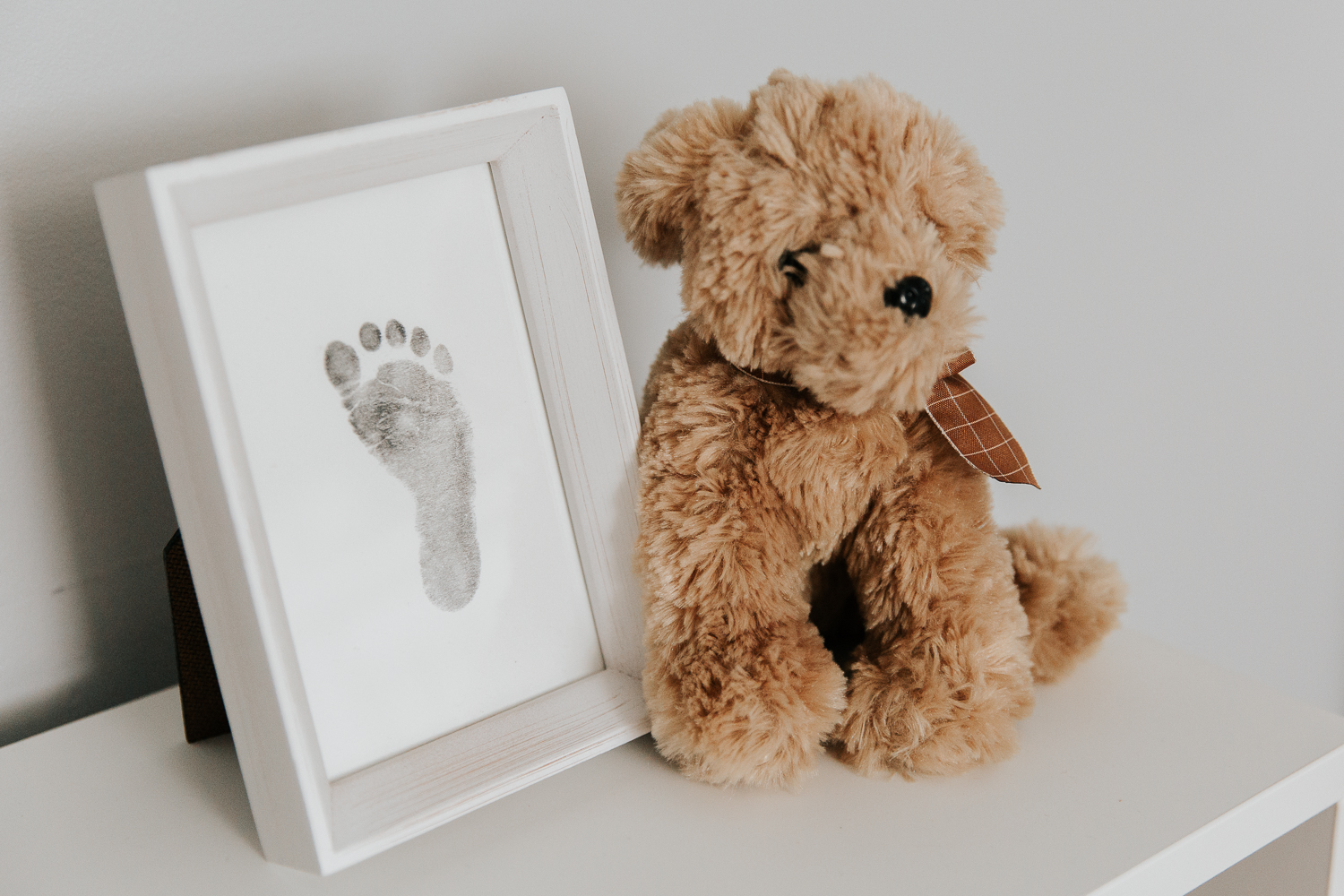 nursery details, stuffed animal dog sitting on shelf next to framed baby footprint - Barrie Lifestyle Photography