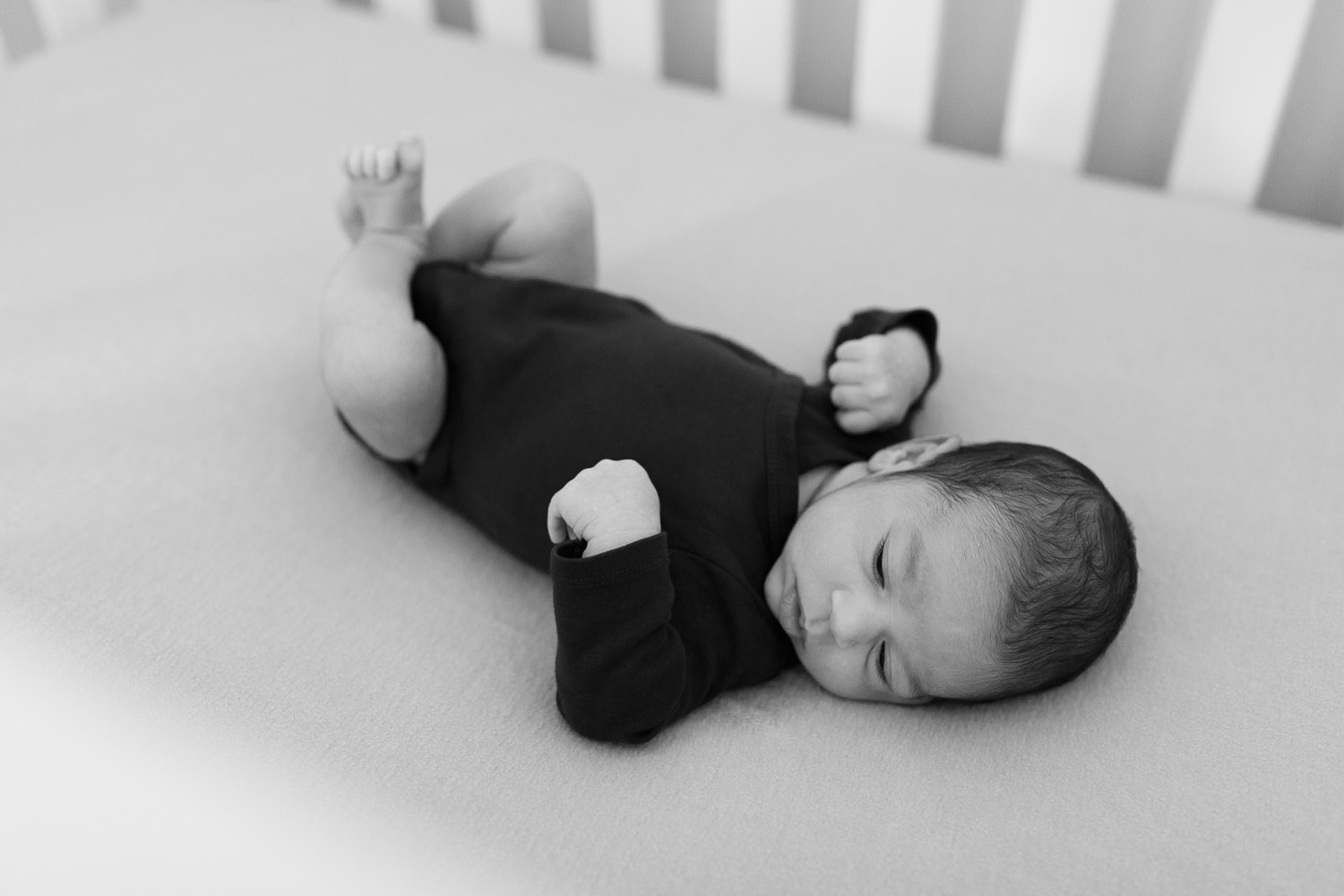 2 week old baby boy with dark brown hair lying in crib in nursery - York Region Lifestyle Photos