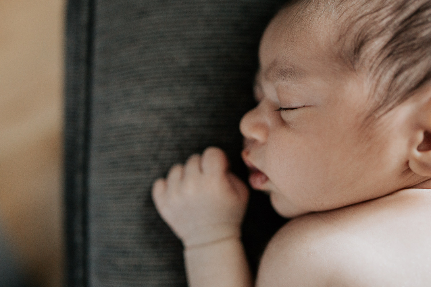2 week old baby boy with dark hair sleeping on stomach on dark grey chair, close up of face and eyelashes - Barrie In-Home Photos