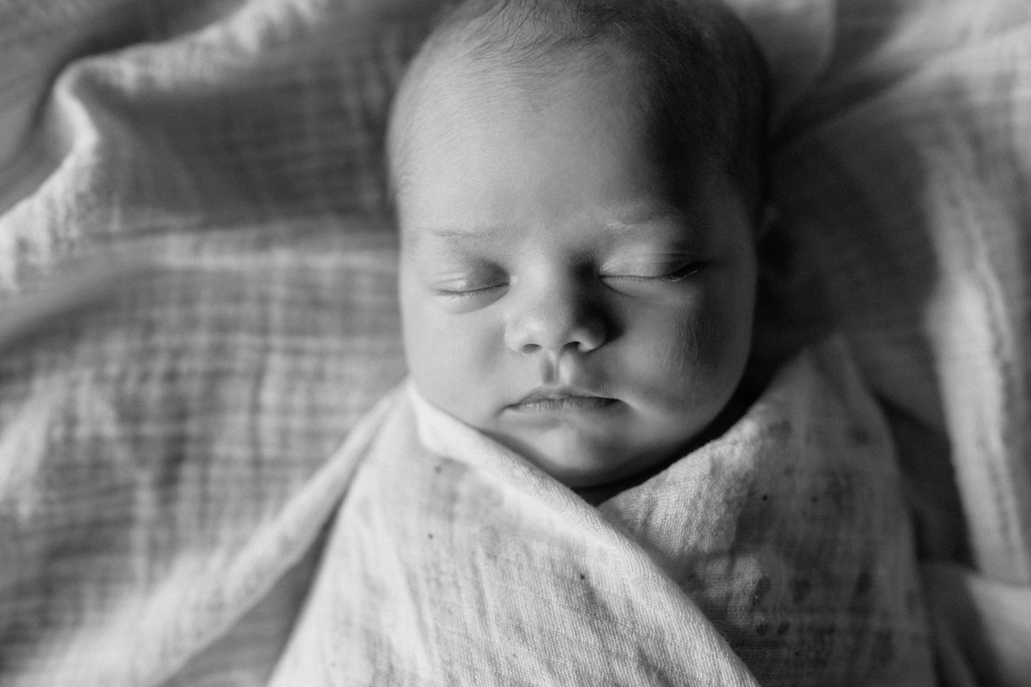 2 week old baby girl with light hair lying on bed wrapped in swaddle, asleep - GTA In-Home Photography